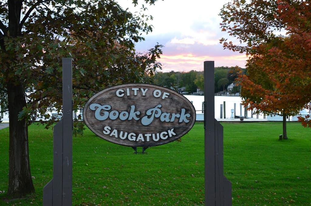 The carved Cook Park sign on a lawn ringed by autumn trees
