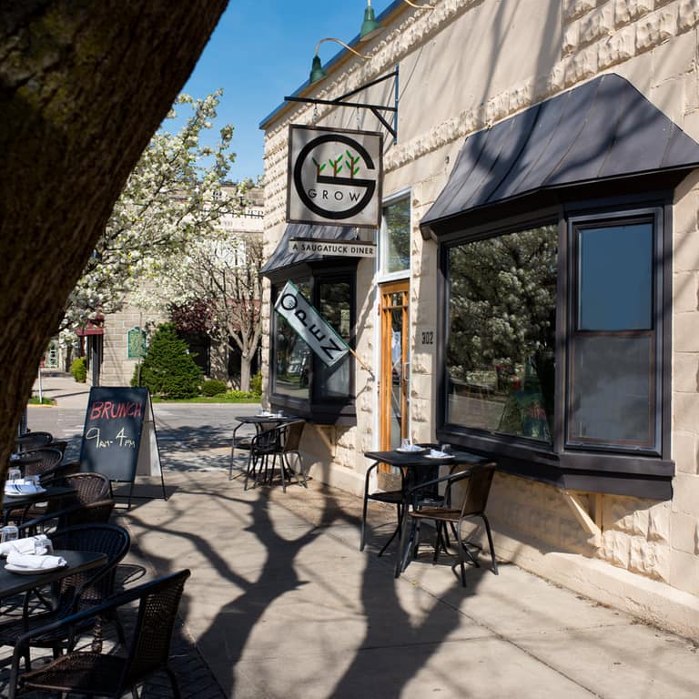 A downtown Saugatuck storefront and sidewalk café tables in spring sunshine