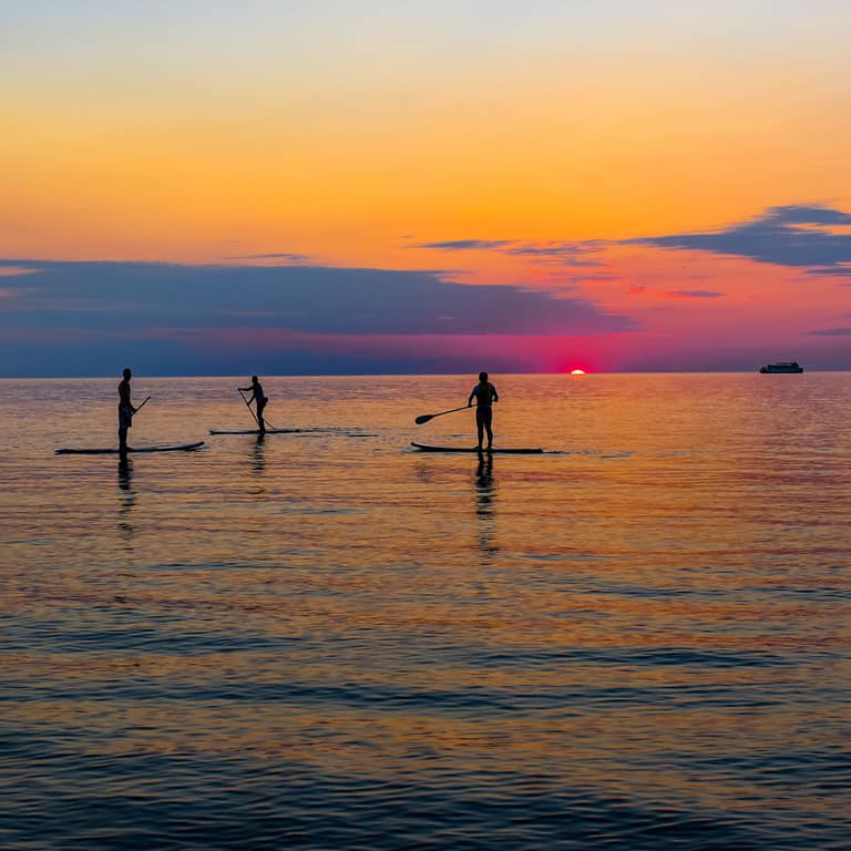 Paddleboarders on Lake Michigan at sunset off Oval Beach